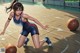 A woman in a basketball uniform dribbling a basketball on a court.