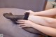 A woman is sitting on a couch with her legs crossed.