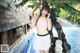 A woman in a pink top and white skirt posing by a pool.