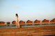 A woman in a white dress standing on a wooden bridge.