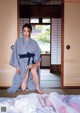 A woman in a blue and white striped kimono sitting on a bed.