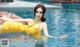 A woman in a yellow bathing suit floating in a pool.