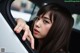 A woman with long brown hair is looking out the window of a car.