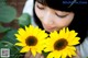 A woman holding two yellow sunflowers in her hands.