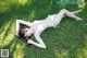 A woman in a white bikini laying on the grass.